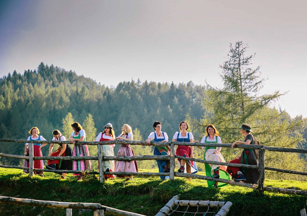 Eine Gruppe Frauen in traditionellem Dirndl Gewand auf einer Alm