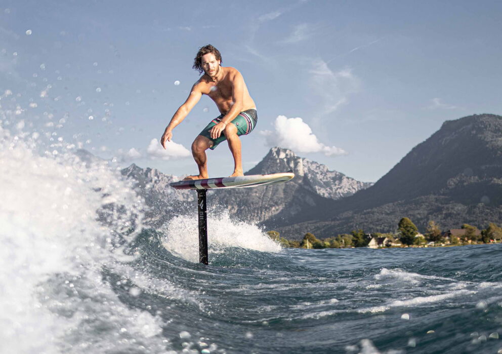 Mann am Surfen auf dem Wolfgangsee mit atemberaubender Bergkulisse