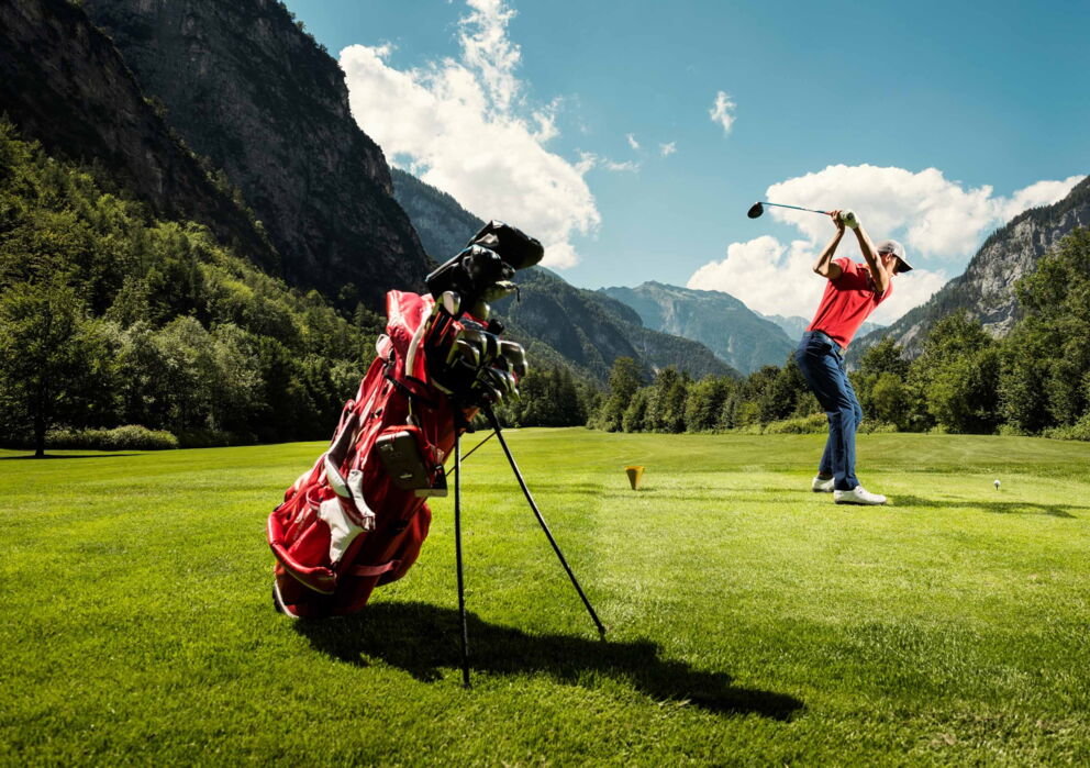 Golf spielender Mann inmitten der Golfanlage in Sankt Wolfgang zwischen atemberaubenden Berglandschaften