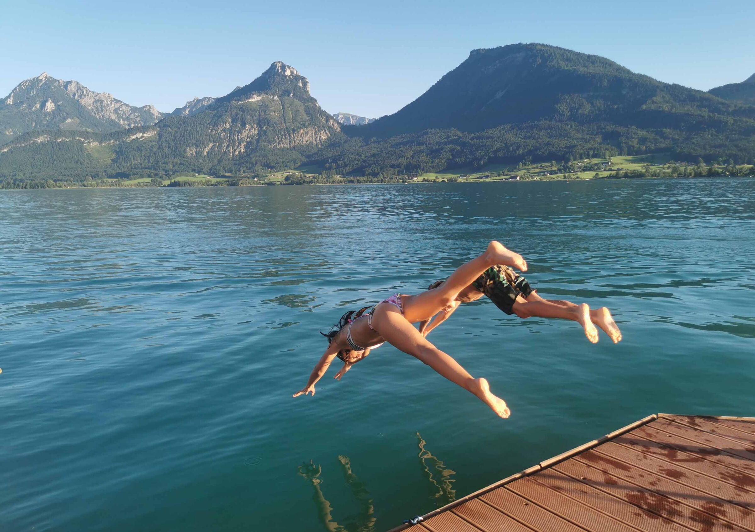 Two children take a dive into the lake Wolfgangsee
