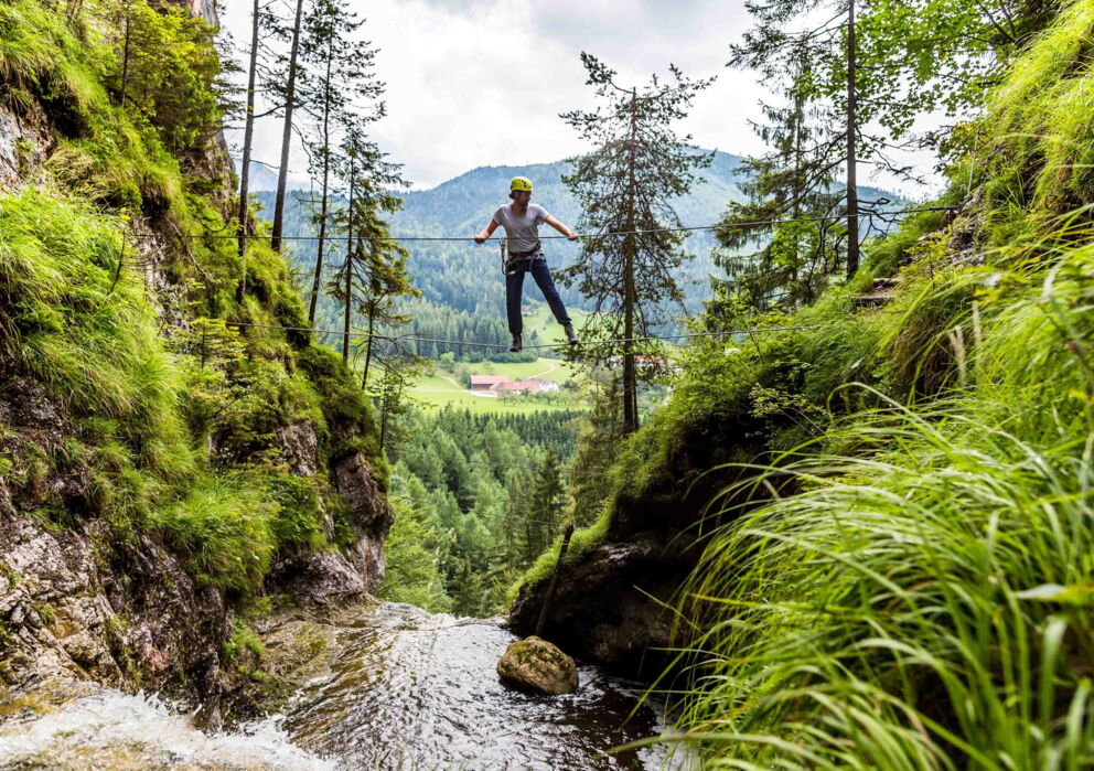 Ein Kletterer an einem Seil kletternd über einen Wasserfall