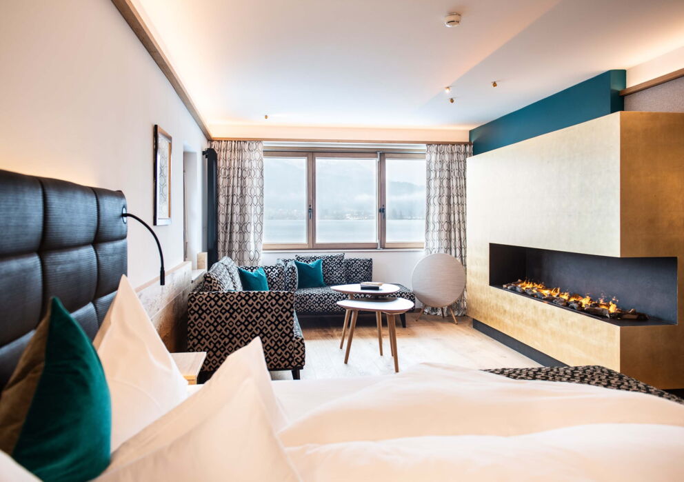 Gemütliches helles Zimmer mit atemberaubenden Blick auf den Wolfgangsee, mit bequemer Wohnlandschaft moderner Architektur und luxuriösen Kamin mitten im Zimmer im Hotel Weisses Rössl