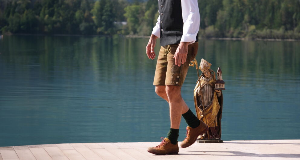Ein Herr spaziert über einen Steg am Wolfgangsee in Lederhose.