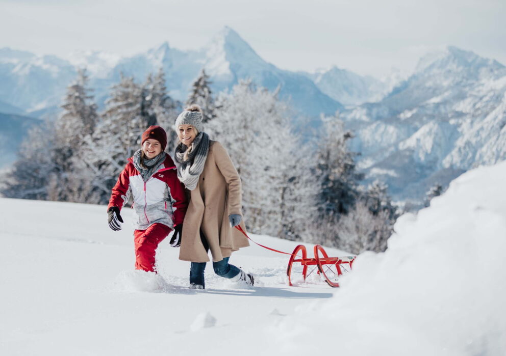 A woman and her child pull a sled through the snow