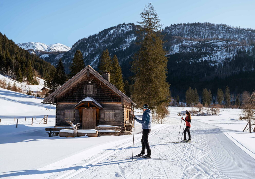 Langlaufen auf einer Langlaufstrecke mitten in den Bergen neben einer Almhütte