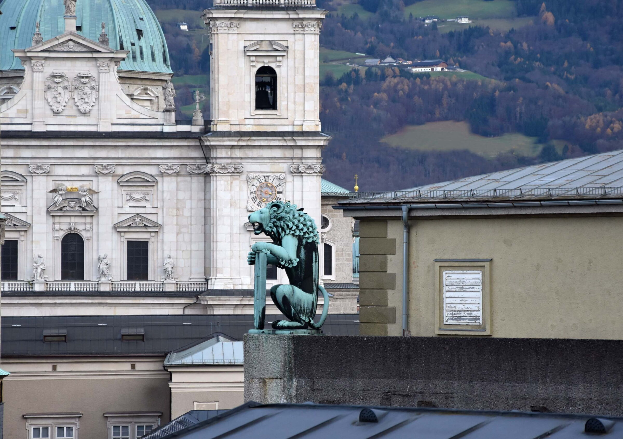 Eine Löwenfigur auf dem Salzburger Festspiel Haus mit dem Salzburger Dom im hintergrund