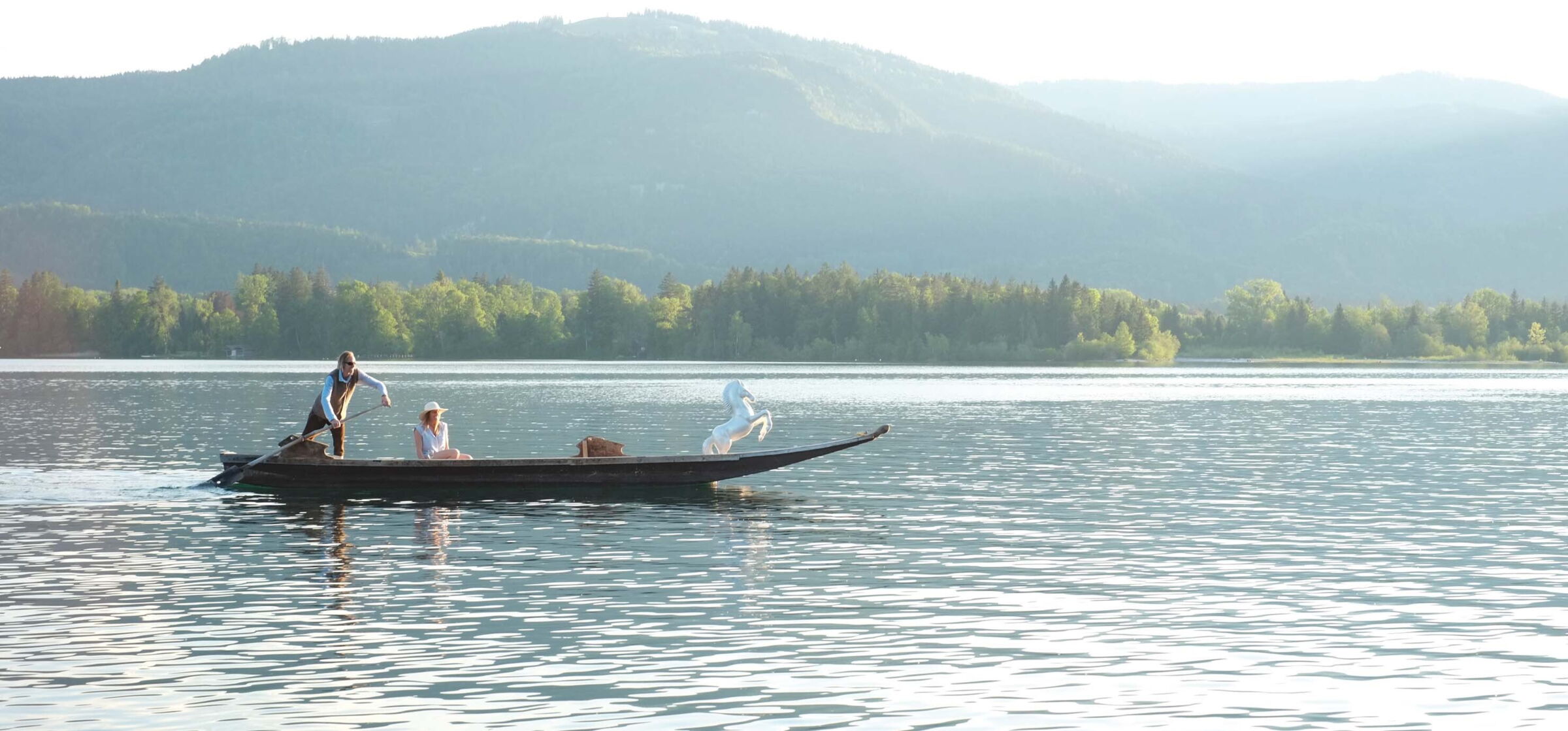 Zwei auf einem kleinen Boot fahrende Menschen am Wolfgangsee