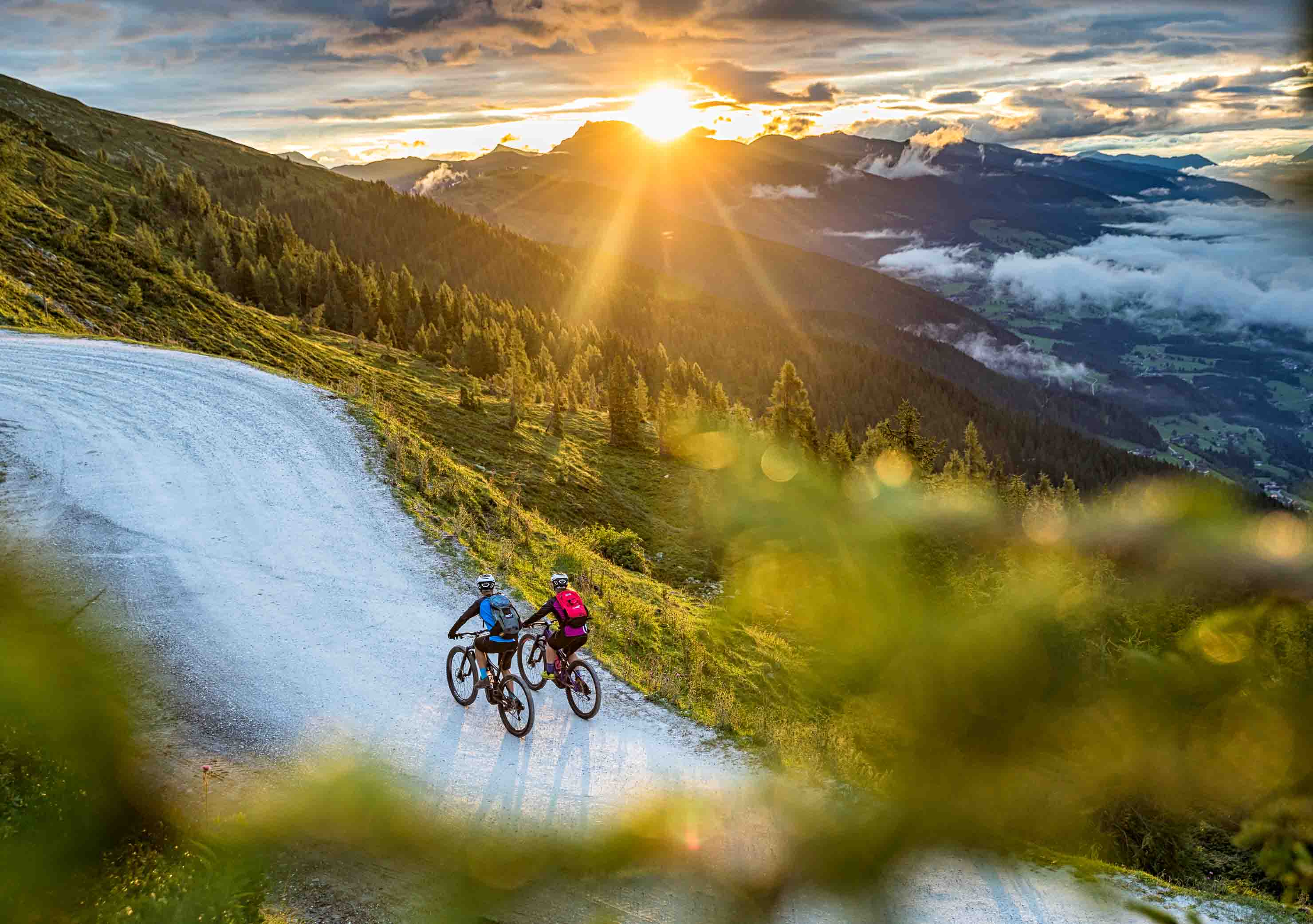 Cyclists on a gravel road in the mountains of the Salzkammergut at sunrise