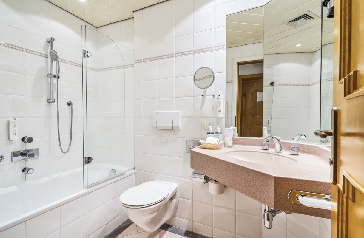 Bathroom with a bathtub, toilet, and sink at the Romantik Hotel Im Weissen Rössl on Lake Wolfgang.