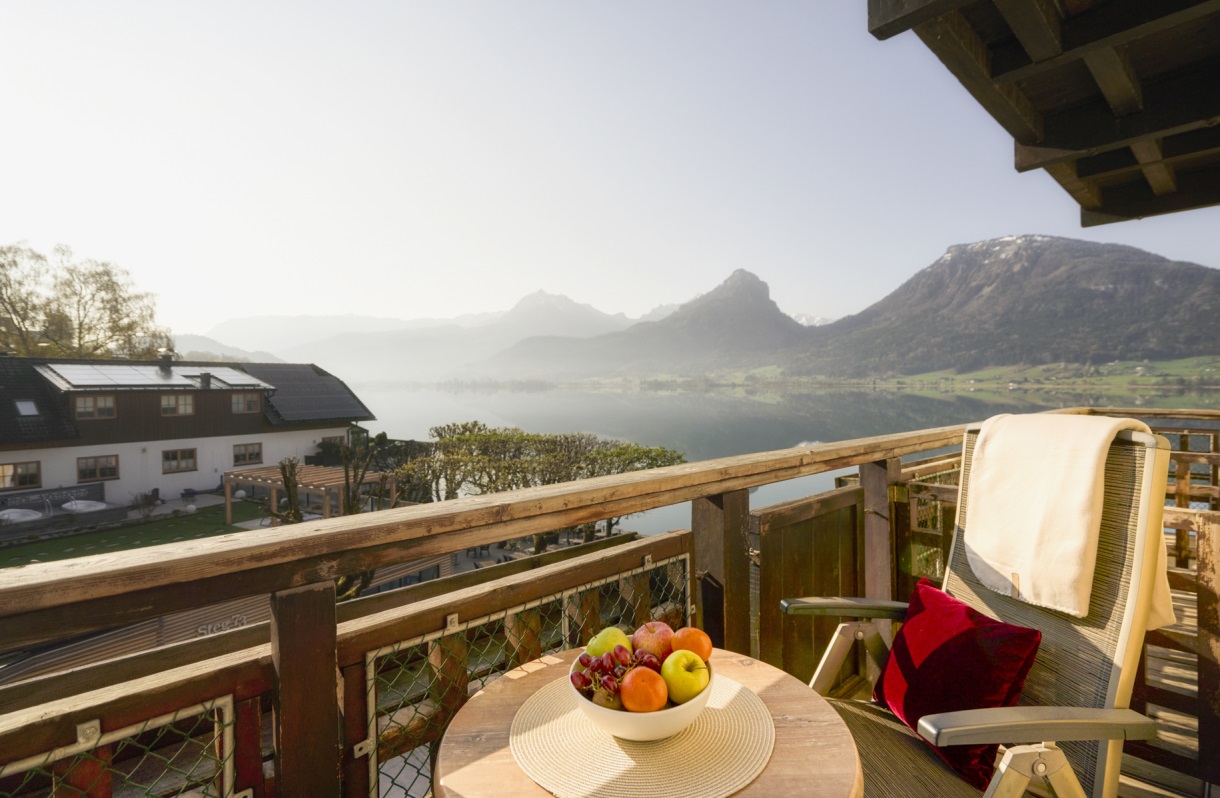 A balcony with a comfortable armchair, a small table, and views of Lake Wolfgang and the surrounding mountain scenery. A quiet spot for relaxing moments at the Romantik Hotel Im Weissen Rössl