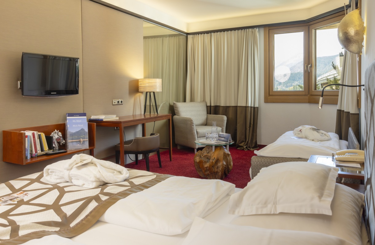 Doppelzimmer im Romantik Hotel Im Weissen Rössl am Wolfgangsee mit Doppelbett, Fernseher, Schreibtisch, Sitzbereich, Beistelltisch und Fenster mit Ausblick.