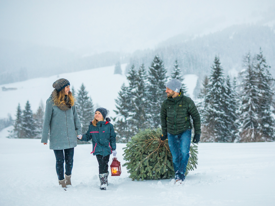 Kleine Familie in verschneiter Landschaft mit einem Christbaum